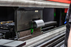 A closeup shot of a CNC press brake machine forming a sheet of metal.