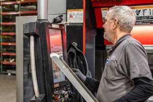 An employee inputting instructions into the computer of the CNC press brake machine.