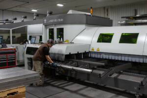Worker removing cut metal tubes from Laser Tube Cutting Machine at Yoder Industries.