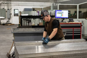 Employee stacking metal tubes that were recently cut by laser tube cutting machine.
