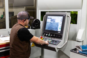 Employee inputting instructions into the computer of the laser tube cutting machine.