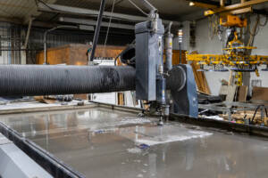 Large Water Jet Machine cutting custom metal pieces in a metal shop.